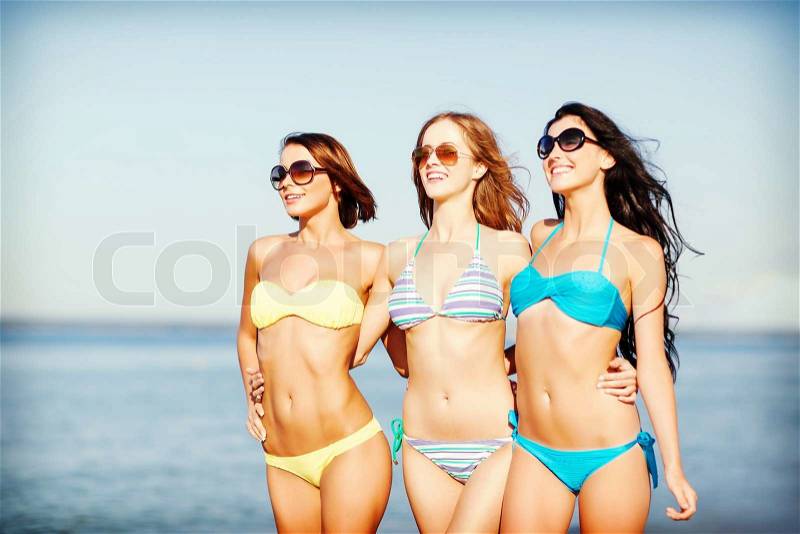 Summer holidays and vacation - girls in shades and bikini walking on the beach, stock photo