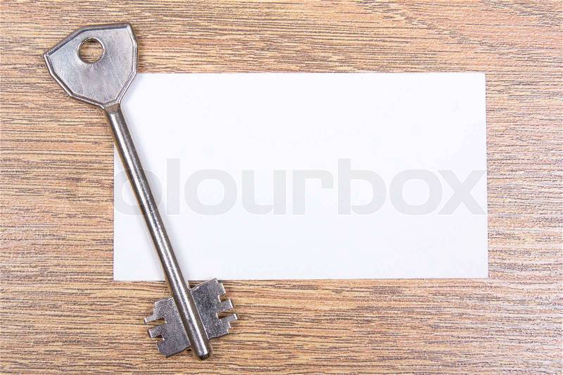 Metal key and visiting card on wooden desktop, stock photo