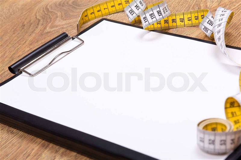 Close up of blank clipboard and measure tape on wooden table, stock photo