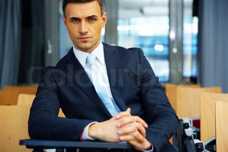 Confident businessman standing at conference hall, stock photo