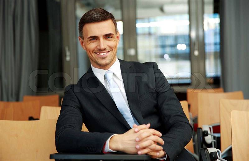 Happy businessman standing at conference hall, stock photo