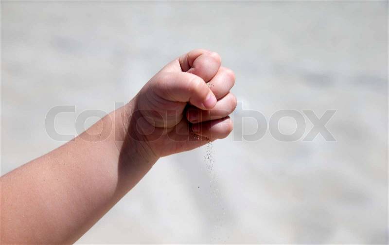 Hand throws sand on the seashore, stock photo