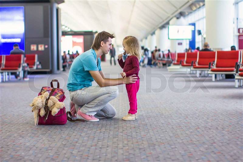 Little girl and young dad in the airport waiting for a flight, stock photo
