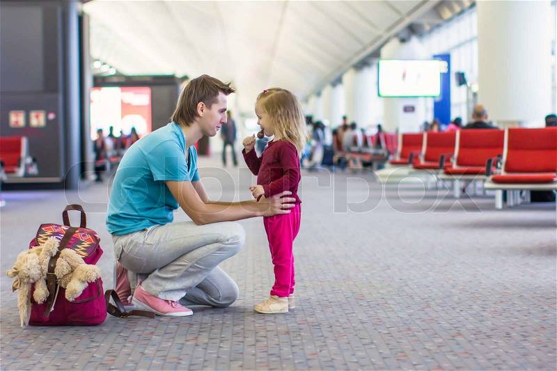Little girl with young dad in the airport waiting for a flight, stock photo