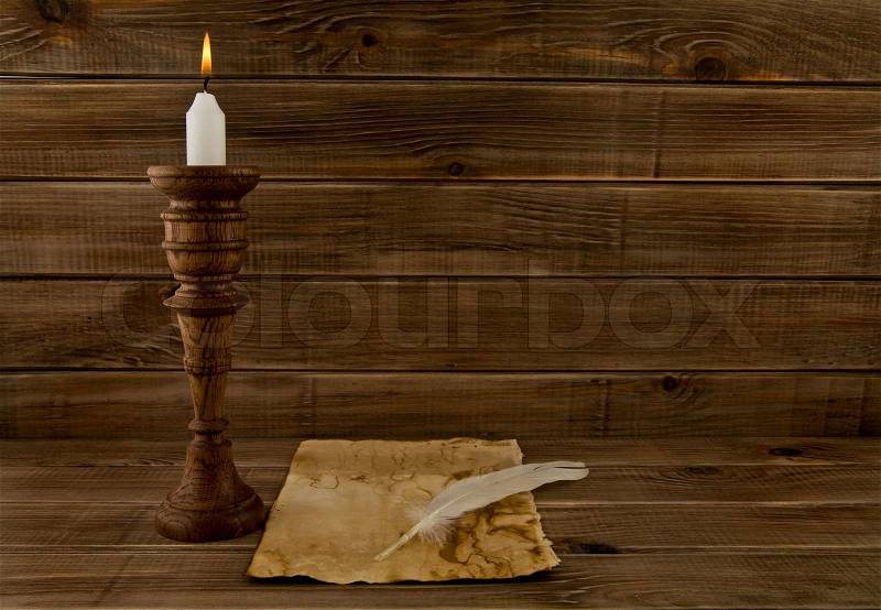 Feather, old paper and candle on a wooden background, stock photo