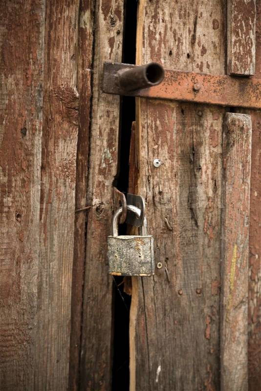 An old wooden door is closed on a ferruginous lock, stock photo