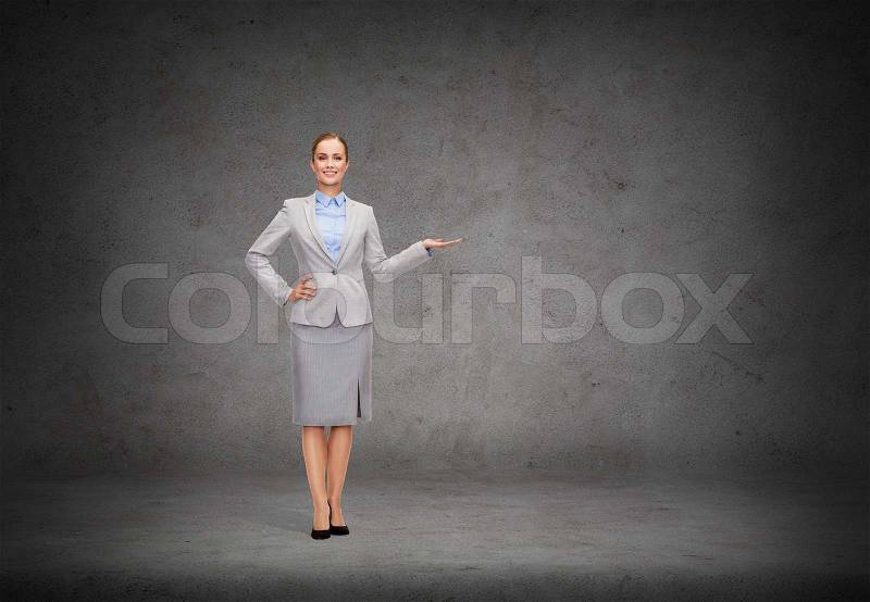 Business and advertisement concept - smiling businesswoman showing something on palm of her hand, stock photo