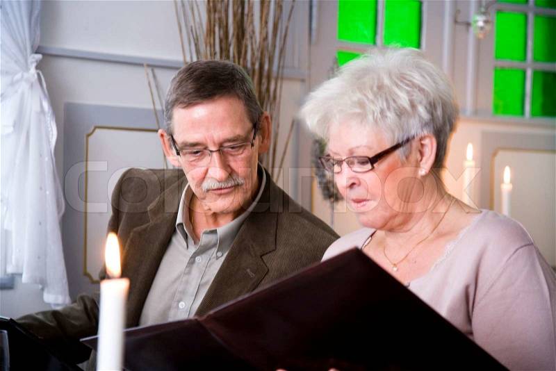 An elderly couple reading a restaurant's menu, stock photo