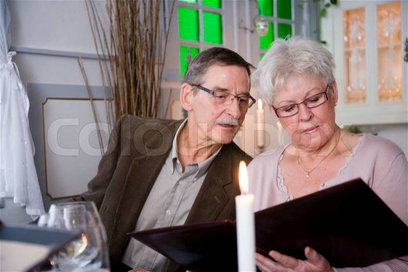 An elderly couple reading a restaurant's menu, stock photo