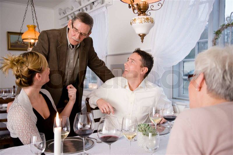 An elderly man talking to his children during a dinner in a restaurant, stock photo