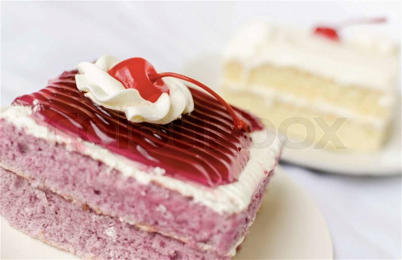Cake with mousse whipping cream and cherry on top. Shallow Depth of field with focus on the cherry, stock photo