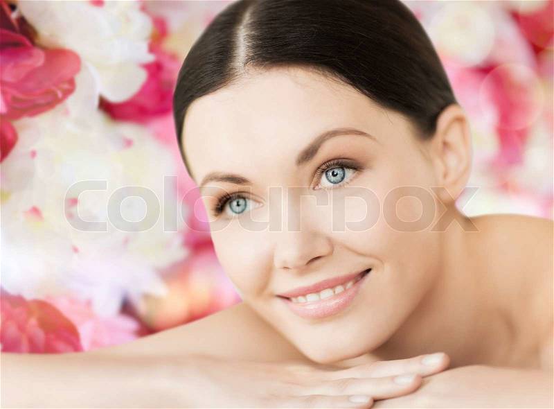 Spa and beauty concept - smiling woman in spa salon lying on the massage desk, stock photo