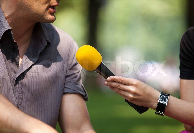 A journalist is making a interview with a microphone, stock photo