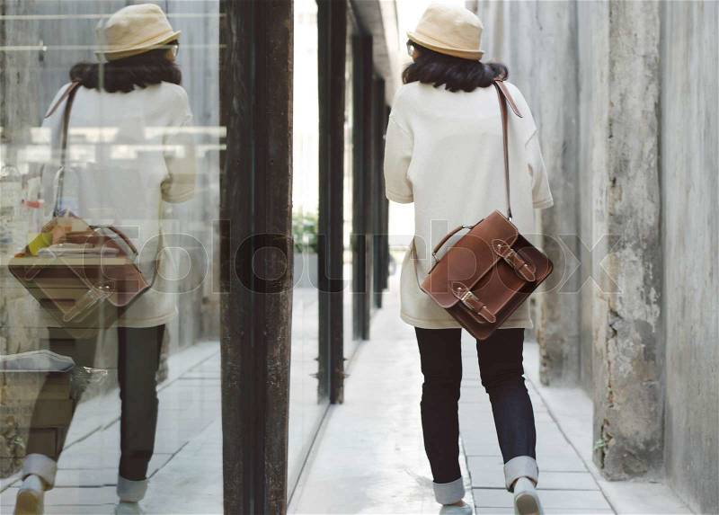 Young fashion girl with leather bag at concrete alleyway, retro filter, stock photo