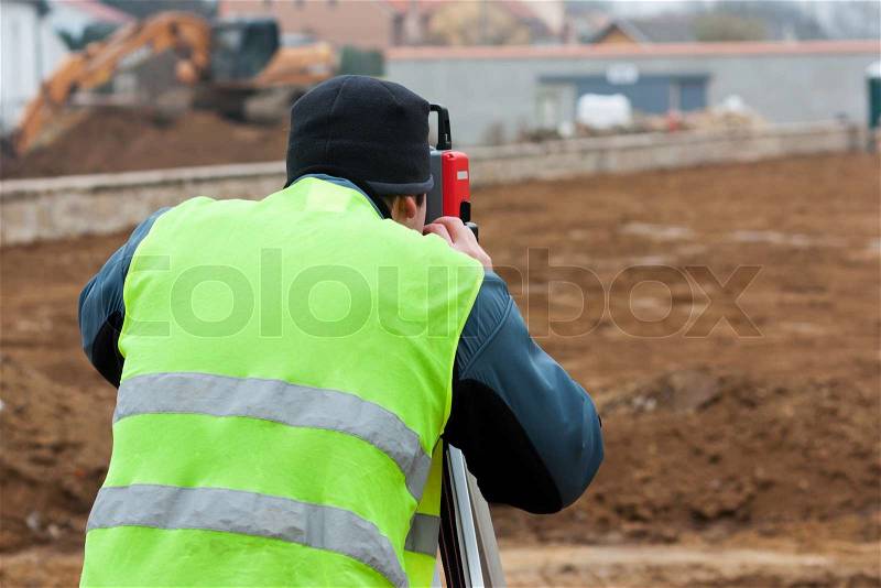Building surveyor taking measurements on a construction site, stock photo