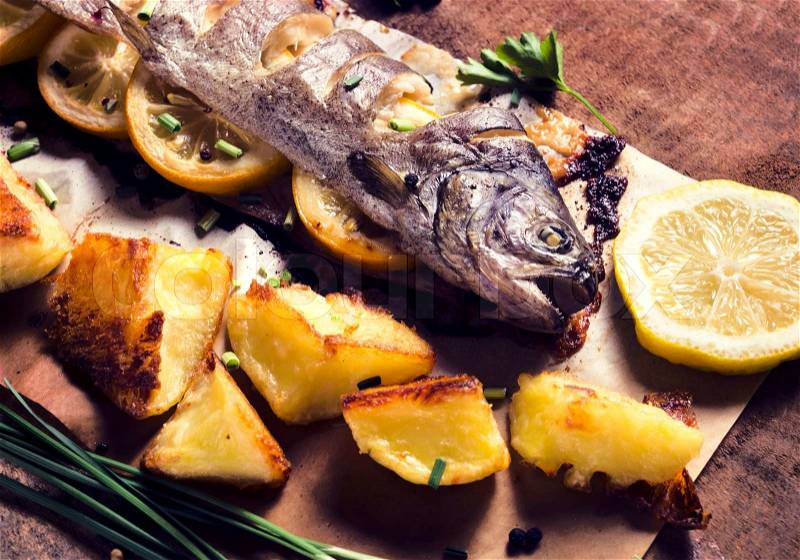 Prepared fish stuffed with lemon and baked potato.Selective focus on the fish head , stock photo