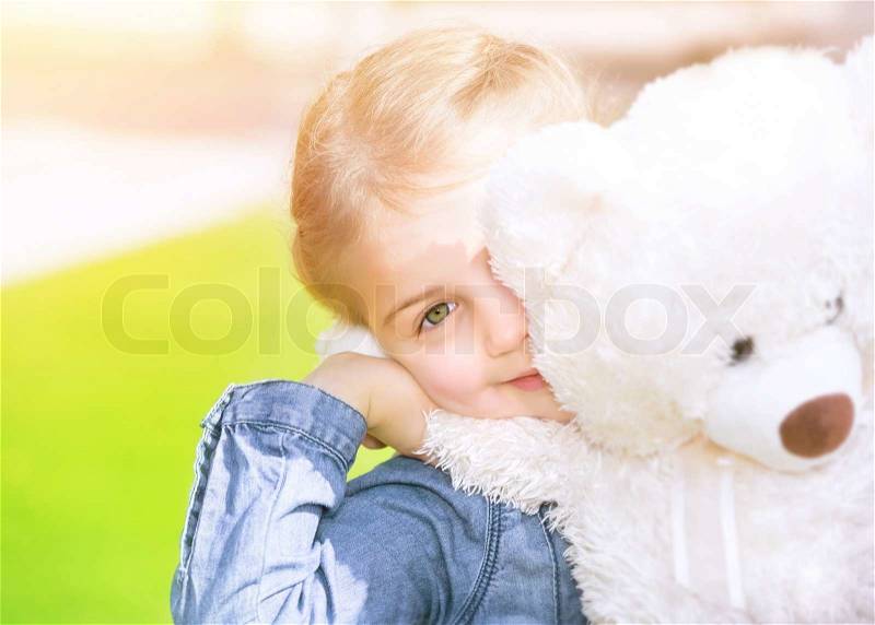 Cheerful little girl with soft bear toy playing outdoors, having fun on backyard in sunny day, summer holidays, happy childhood concept , stock photo