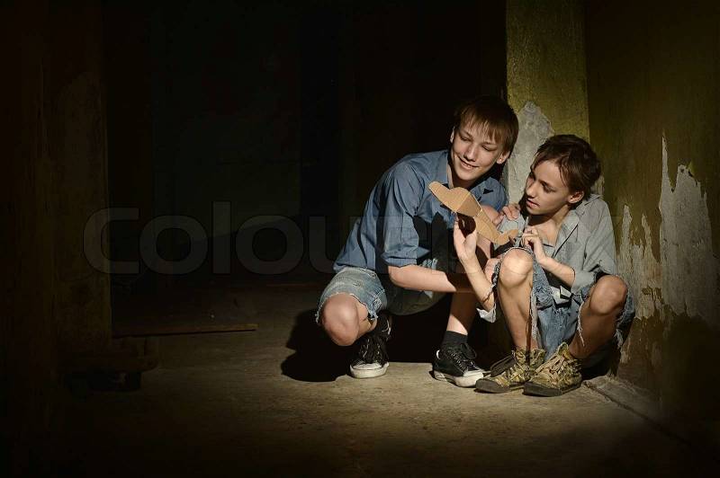 Two Lonely little boys with paper plane in a dark cellar, stock photo