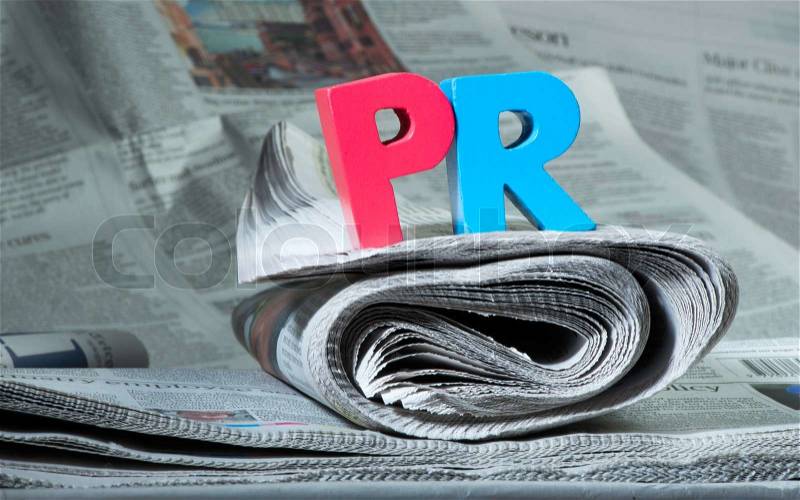 Word PR on newspaper. Wooden letters, stock photo