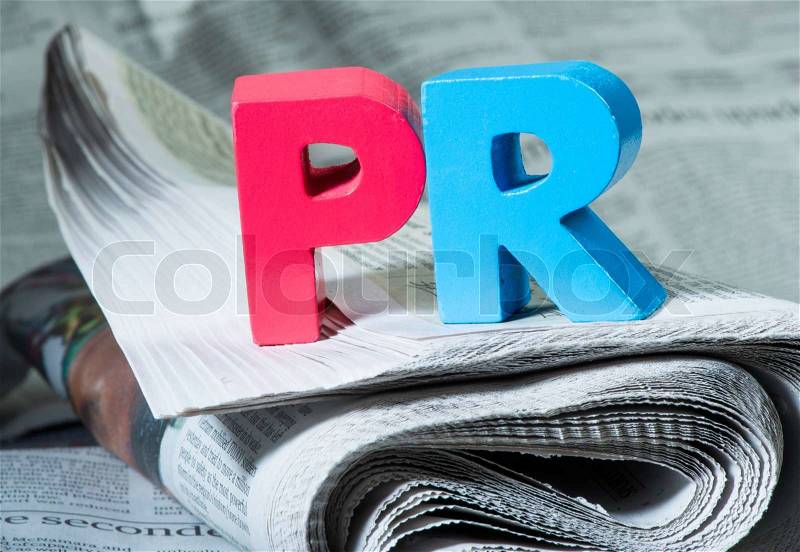 Word PR on newspaper. Wooden letters, stock photo