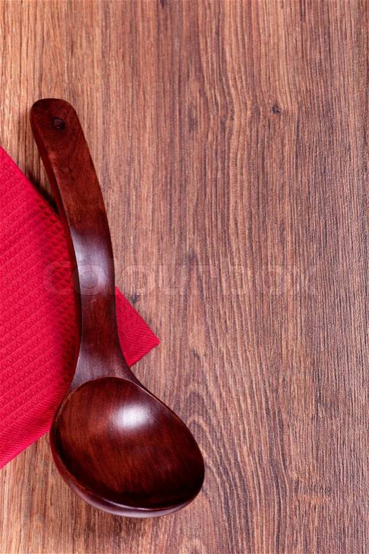 Red wooden spoon on a red towel and wooden background wooden background, stock photo