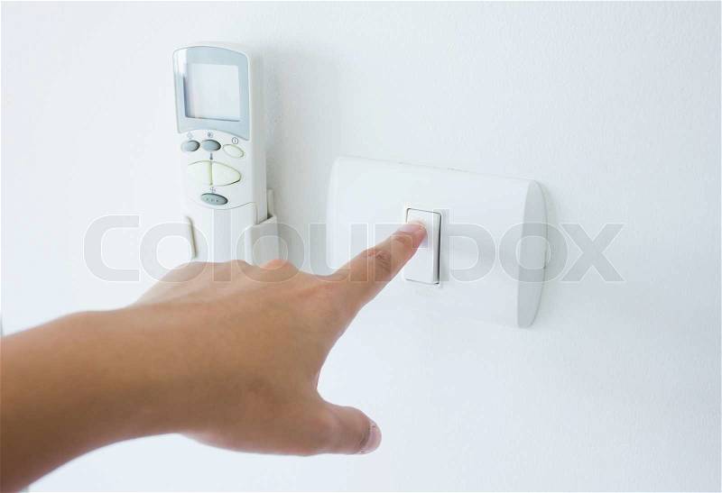 Womans hand with finger on light switch, about to turn off the lights, stock photo