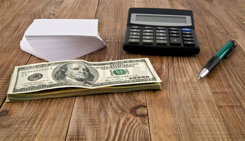 Calculator, dollars, pen and paper on the table, stock photo