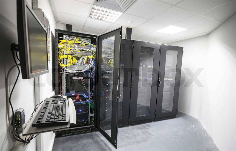Modern server room interior with black computer cabinets and user terminal, stock photo