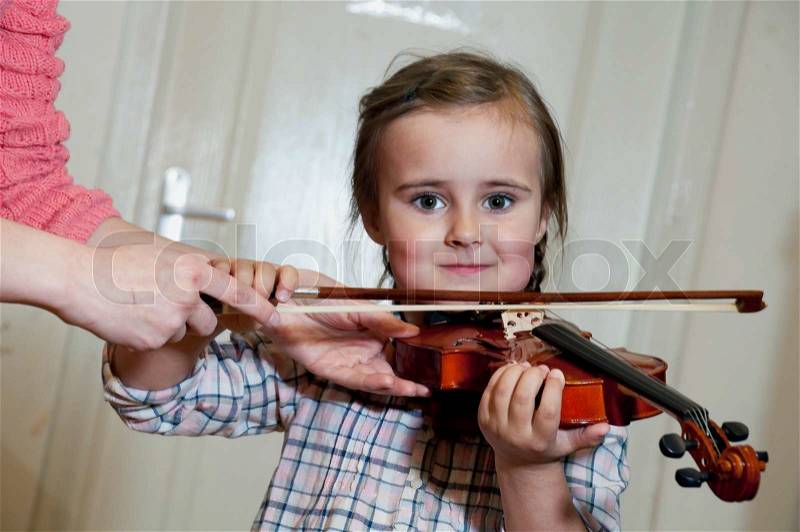 Cute 3 year old preschool girl learning violin playing at music school, stock photo