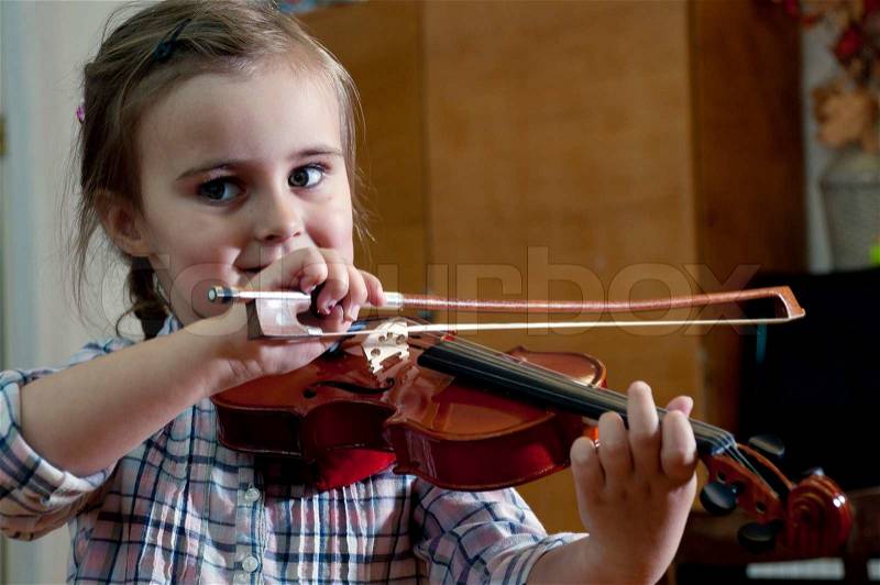 Adorable 3 year old little girl learning playing violin on music school class. First steps, stock photo