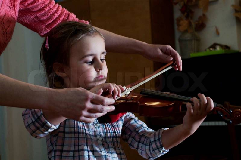 Adorable 3 year old little girl learning playing violin at music school class. First steps, stock photo