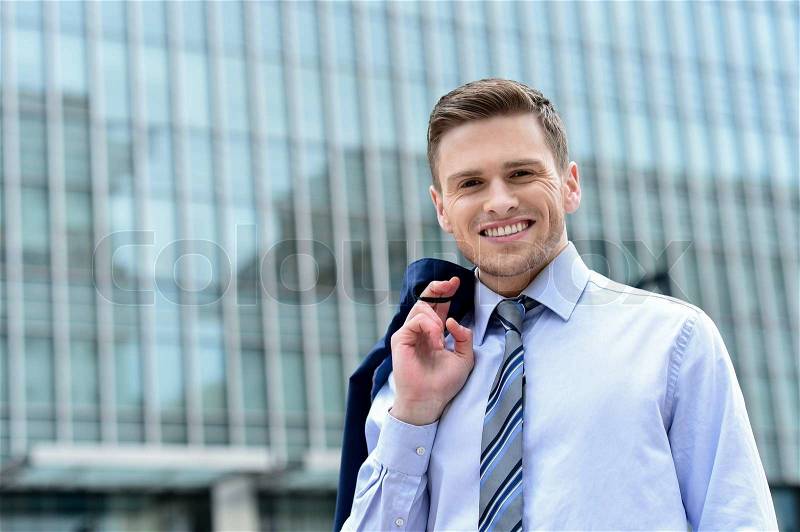 Smiling businessman holding his suit jacket on his shoulder, stock photo