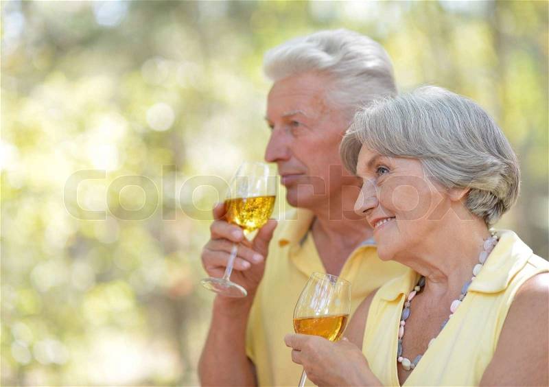 Beautiful older couple drinking wine on nature, stock photo