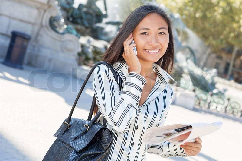 Beautiful asian tourist on the phone and holding a city tour map, stock photo