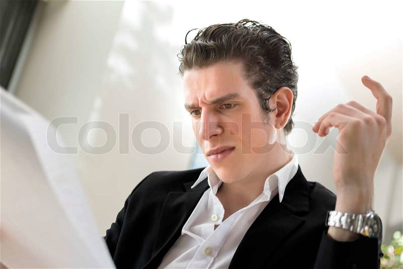 Male business looking wondering at his papers. Wondering what is going on, stock photo