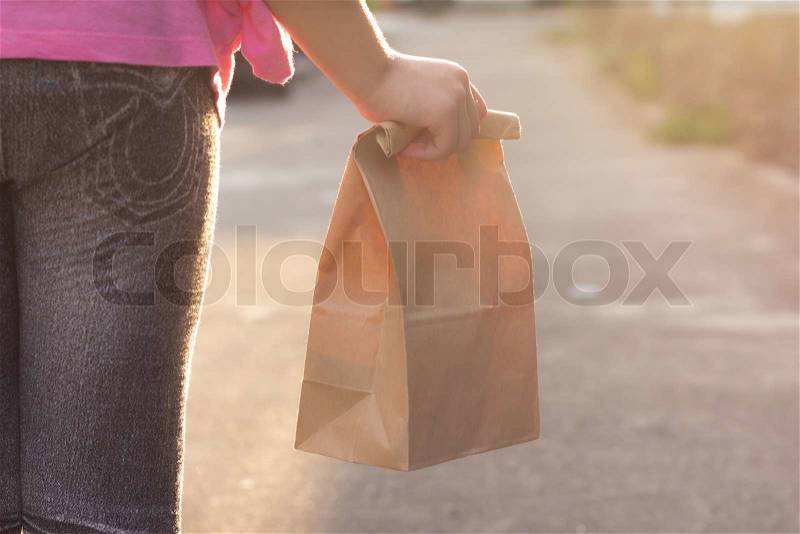 Child walking to school, with paper lunch bag, stock photo