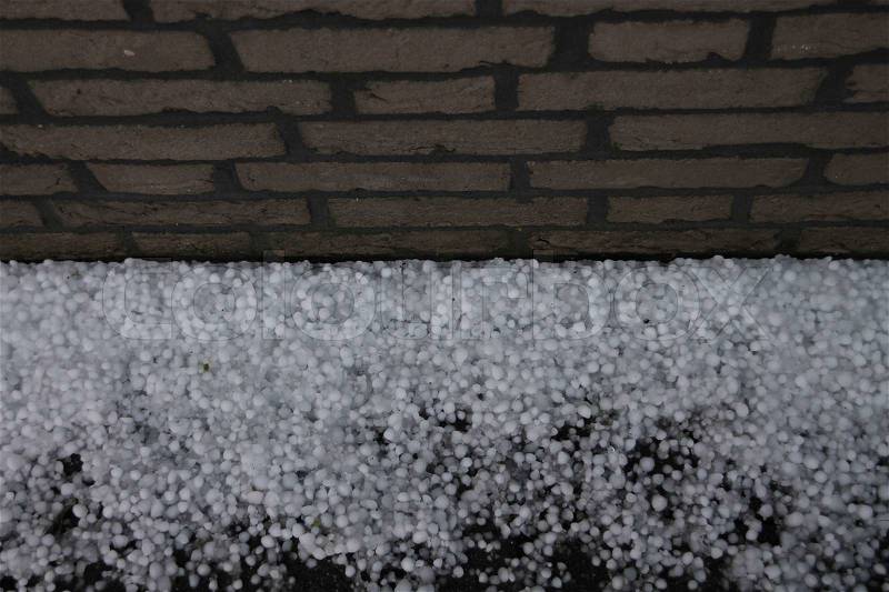 After the hailstorm, the wall and many fallen hailstones on the road in spring, global warming?, stock photo