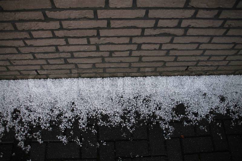 After the hailstorm, the wall and many fallen hailstones on the road in spring, global warming?, stock photo