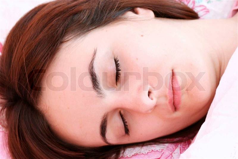 Beautiful young woman sleeping on bed in her bedroom at home in the morning, stock photo