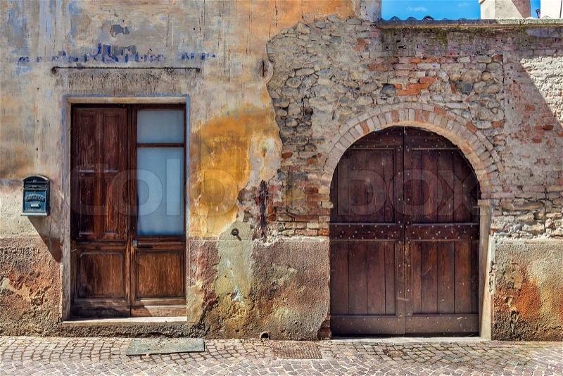 Wooden door, gate and letter box at the entrance to old abandoned brick house in small italian town, stock photo