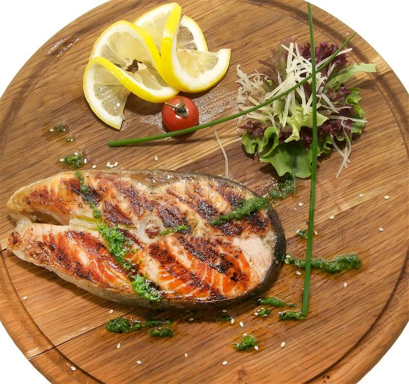 Wooden plate with a piece of fish cooked on the grill, stock photo