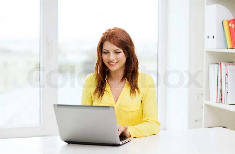 Education, e-learning and technology concept - smiling student with laptop computer at school, stock photo
