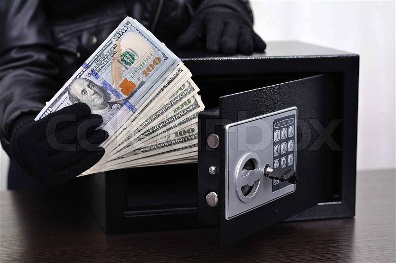 Thief steals dollars from the safe, close up, stock photo