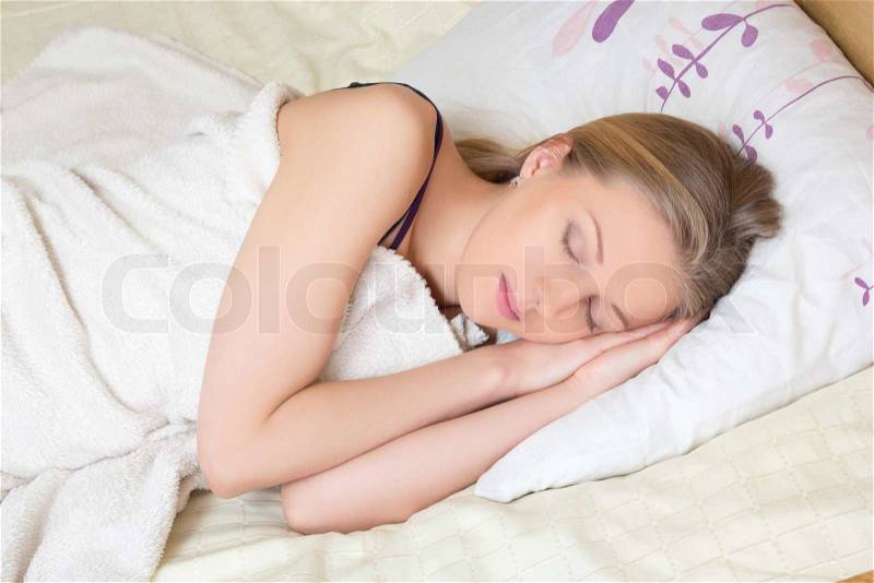 Cute young blondie woman sleeping on bed, stock photo