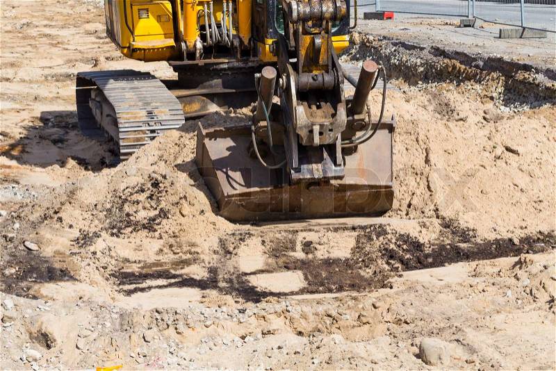 Heavy duty, industrial excavator moving soil and sand on road construction site, stock photo