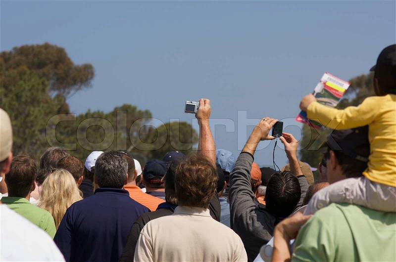 Fans huddle to get a glimpse of Tiger Woods warming up at the golf range, stock photo