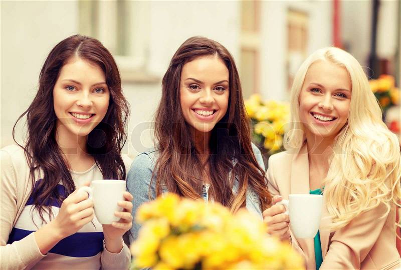 Holidays, food and tourism concept - three beautiful girls drinking coffee in cafe, stock photo