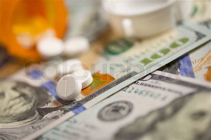 Medicine Pills Scattered on Newly Designed U.S. One Hundred Dollar Bills, stock photo
