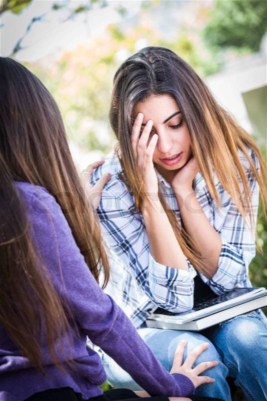Sad or Stressed Young Mixed Race Girl Being Comforted By Her Friend Outside on Bench, stock photo