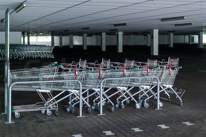 Rows of shopping carts in abandoned car park near entrance of closed supermarket due to public holiday, stock photo